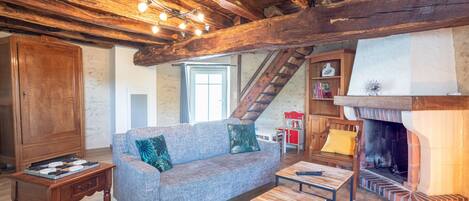 A rustic interior with exposed wooden beams, a fireplace, a sofa, and a wooden table.