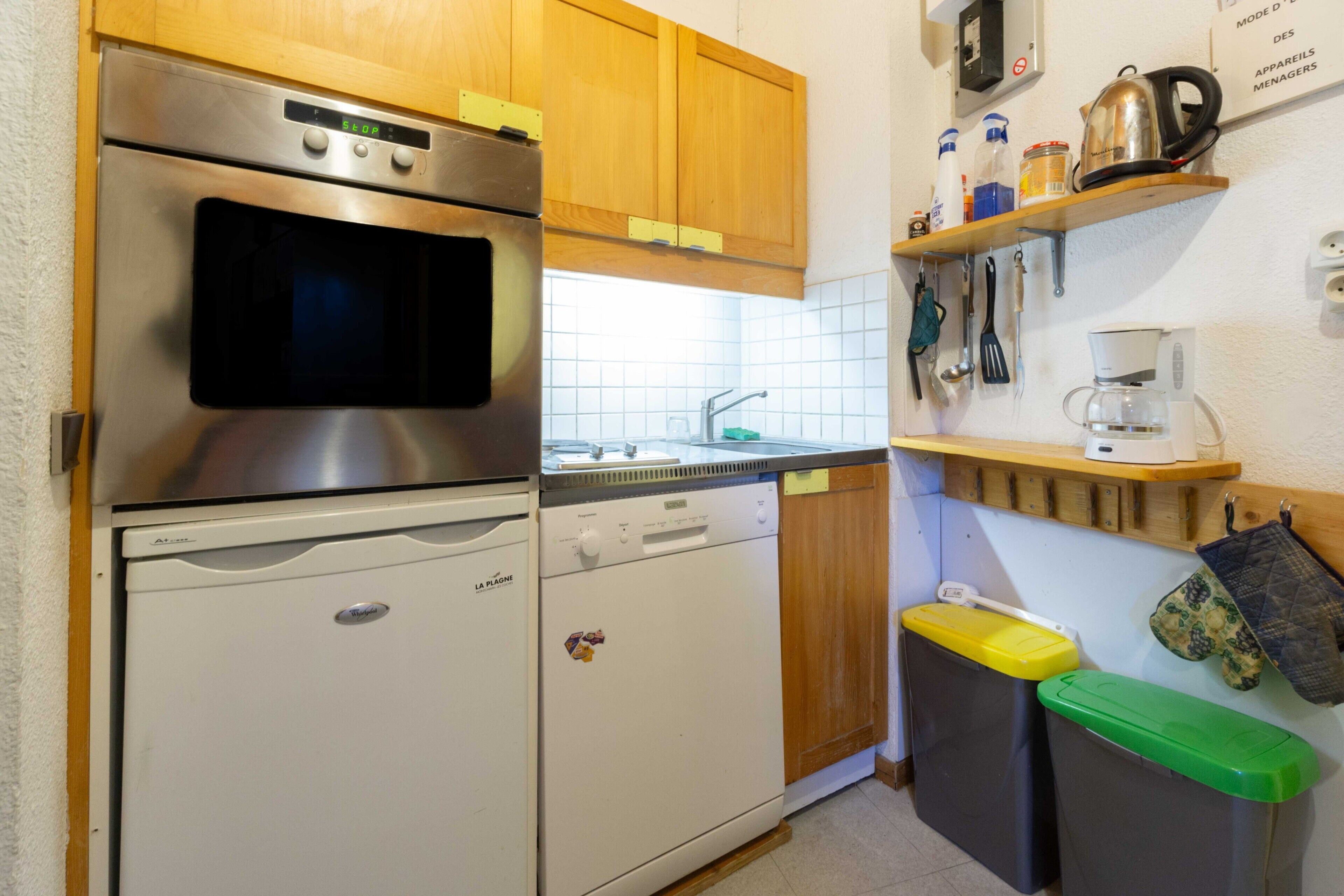 A compact kitchen with a dishwasher, oven, and sink.