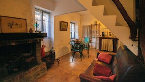 Un salon chaleureux avec une cheminée, une table à manger avec des chaises, un escalier et une vue sur l’espace repas.