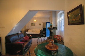 Una sala de estar acogedora con un sofá, una mesa con una maceta de barro y una escalera que lleva a otra habitación.