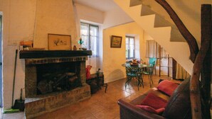 Un salon avec une cheminée, un coin repas avec une table et des chaises, et un escalier.