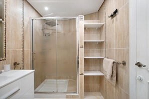 Ein modernes Badezimmer mit einer Glaskabine zur Dusche, einem weißen Waschbecken und einem Handtuchhalter.