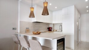A modern kitchen with white cabinetry, a marble countertop, and two pendant lights. - Studio Apartment "Puerto Marina Luxury" with Sea View & Wi-Fi (Benalmádena)