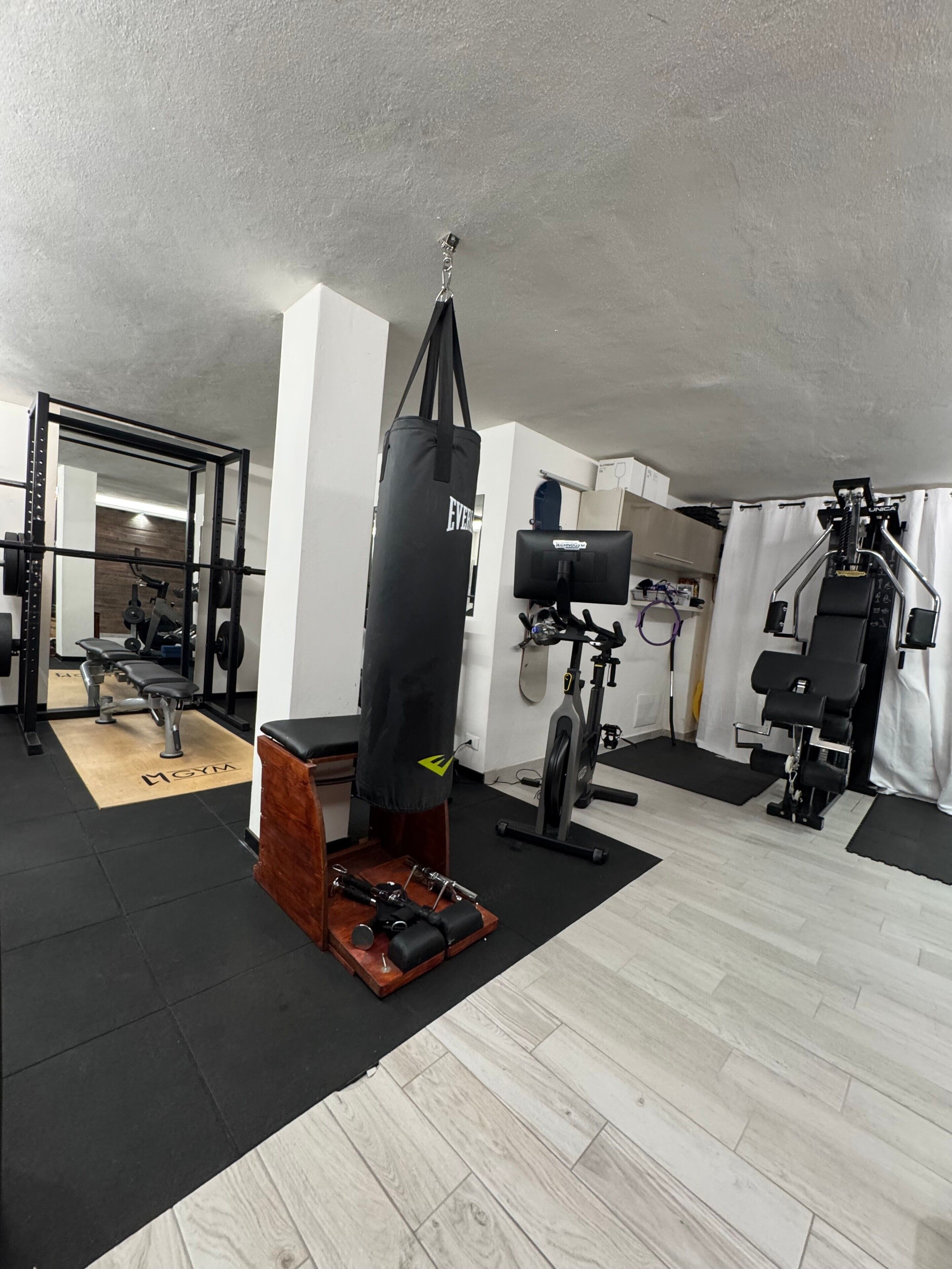 Een fitnessruimte met een bokszak, een halterbank en trainingsapparatuur.