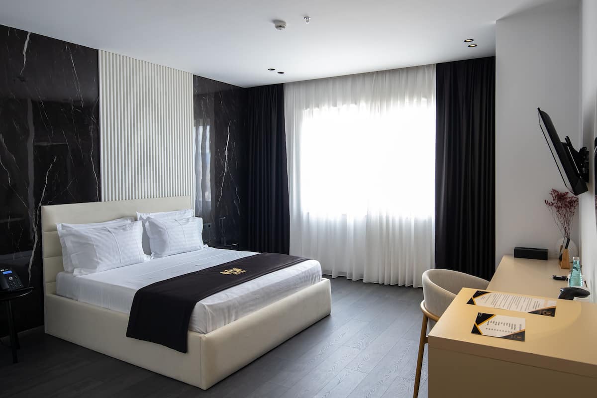 A modern hotel room with a large bed, a desk, and a chair.