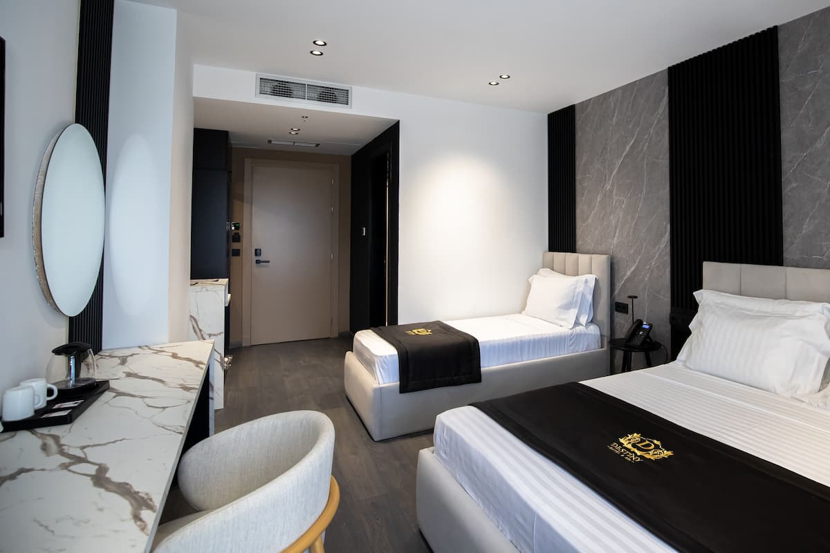 A hotel room with two beds, a desk with a chair, a mirror, and a marble wall.