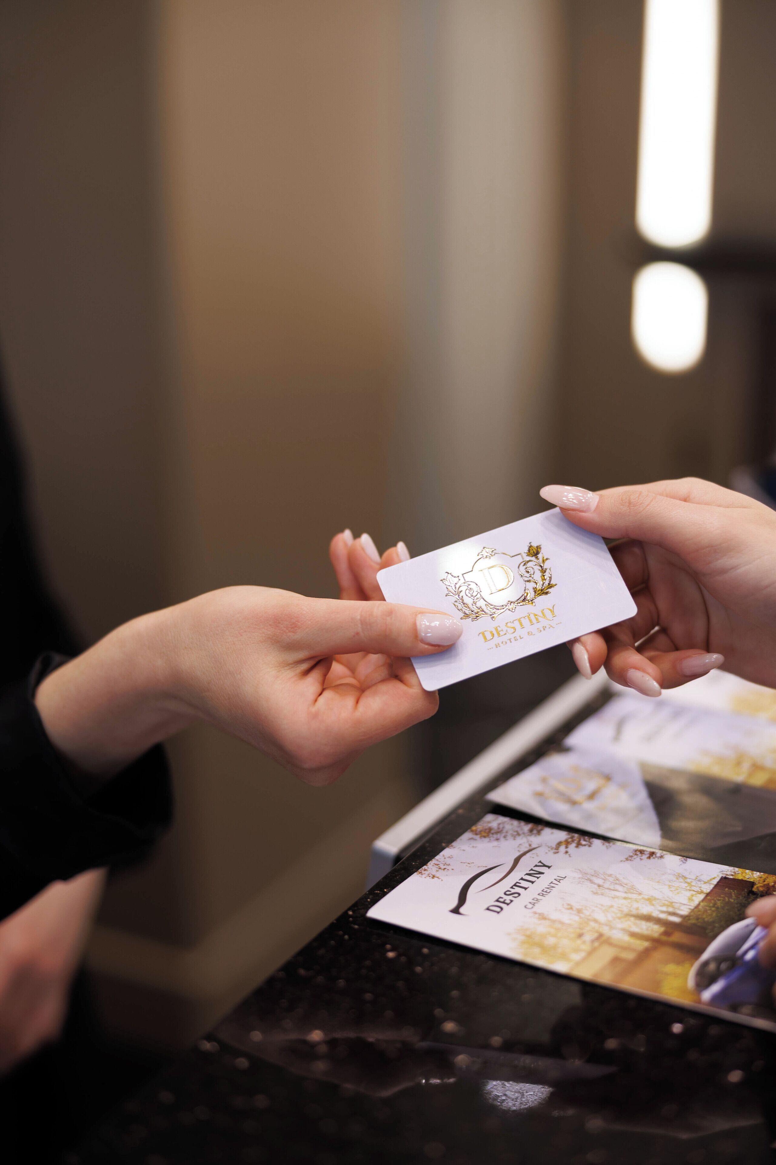 A hand holding a business card with the text "DESTINY HOTEL & SPA".