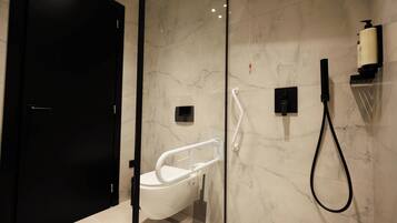 A modern bathroom with a glass shower enclosure, a white toilet, and a black door.