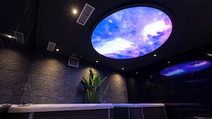 A modern spa area with a large circular skylight displaying a starry sky, a reception desk, and a wooden bench. - Destiny Hotel (Kashar)