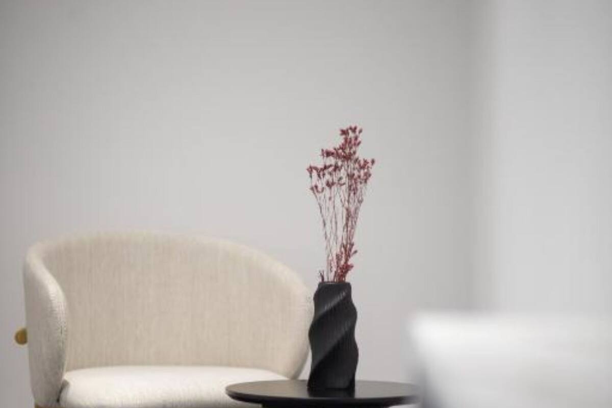 A minimalist room with a light-colored sofa, a small round table, and a vase with dried branches.