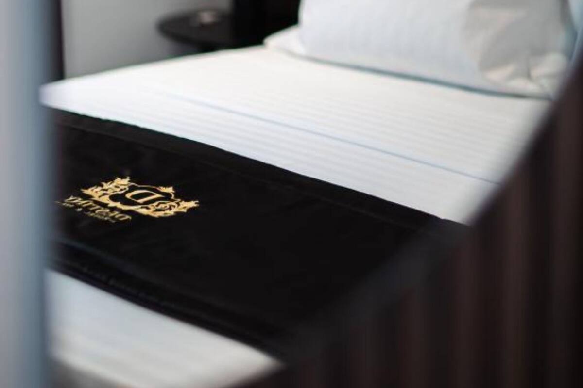 A neatly made bed with white linens and a black headboard.