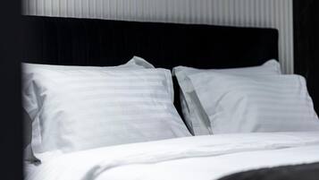 Una cama con ropa blanca y cabecera negra en una habitación de hotel.
