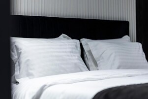 Una cama con ropa blanca y cabecera negra en una habitación de hotel.