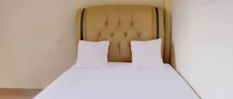 Una cama bien hecha con cabecera capitonada y dos almohadas.