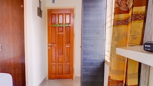 A hallway with a wooden door, a black door, and a curtain with a floral pattern. - OYO Life 92637 Kost Arya Exclusive (Jambi)