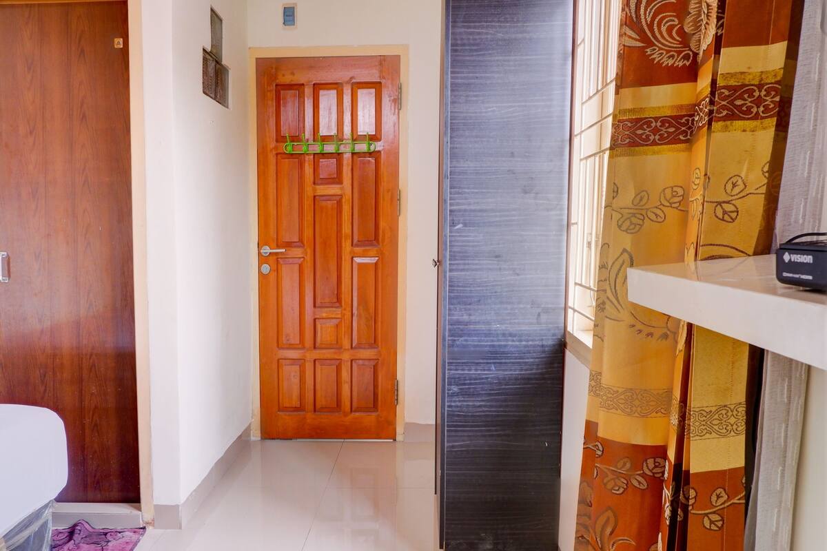 A hallway with a wooden door, a black door, and a curtain with a floral pattern.