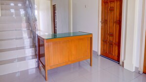 A staircase with a glass-top desk and a wooden door in a hallway. - OYO Life 92637 Kost Arya Exclusive (Jambi)