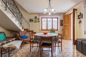 A dining area with a round table, chairs, a staircase, and a wooden door.