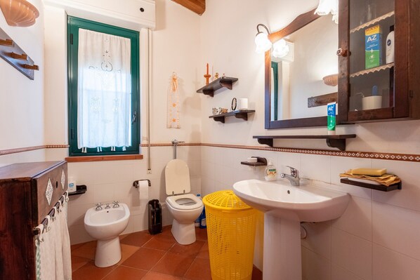 Une salle de bain équipée de toilettes, d’un bidet, d’un lavabo et d’un miroir.