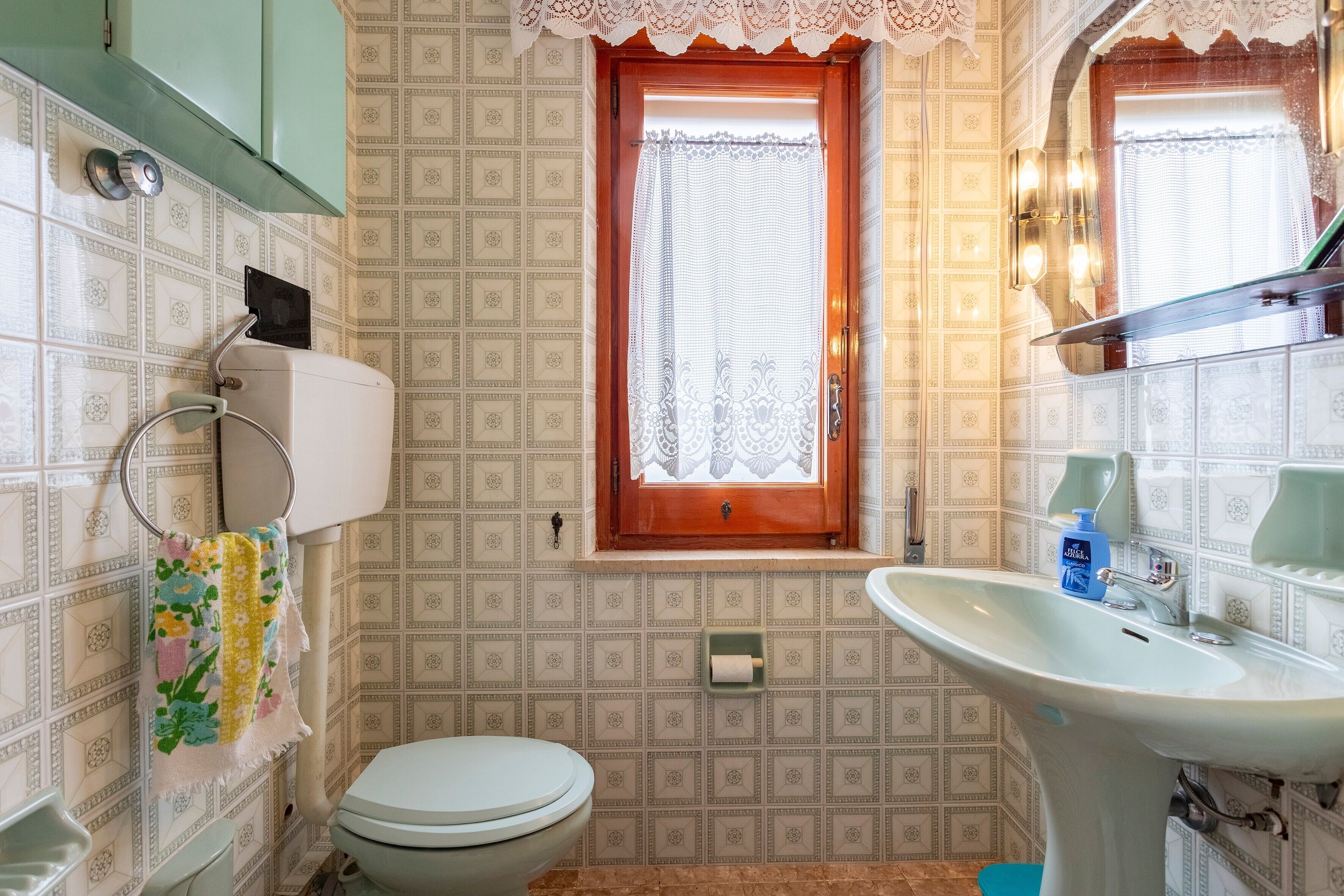 A bathroom with a toilet, sink, and window.