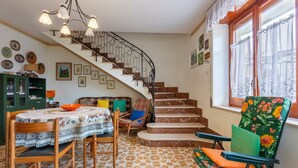 A staircase with a wrought iron railing, a dining area with a table and chairs, and a window with lace curtains. - Holiday Home 'Villa Sofia' with Private Garden and Balcony (Salemi)