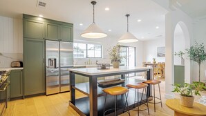 Una cocina moderna con una isla central, taburetes de bar e iluminación colgante.