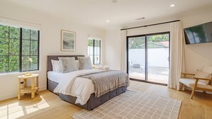 Un dormitorio con una cama, una mesita de noche, un televisor y vistas al exterior.