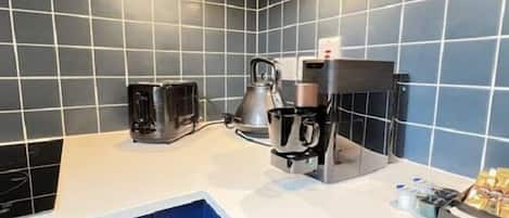 A kitchen with a coffee machine, a kettle, and a coffee grinder on the counter.