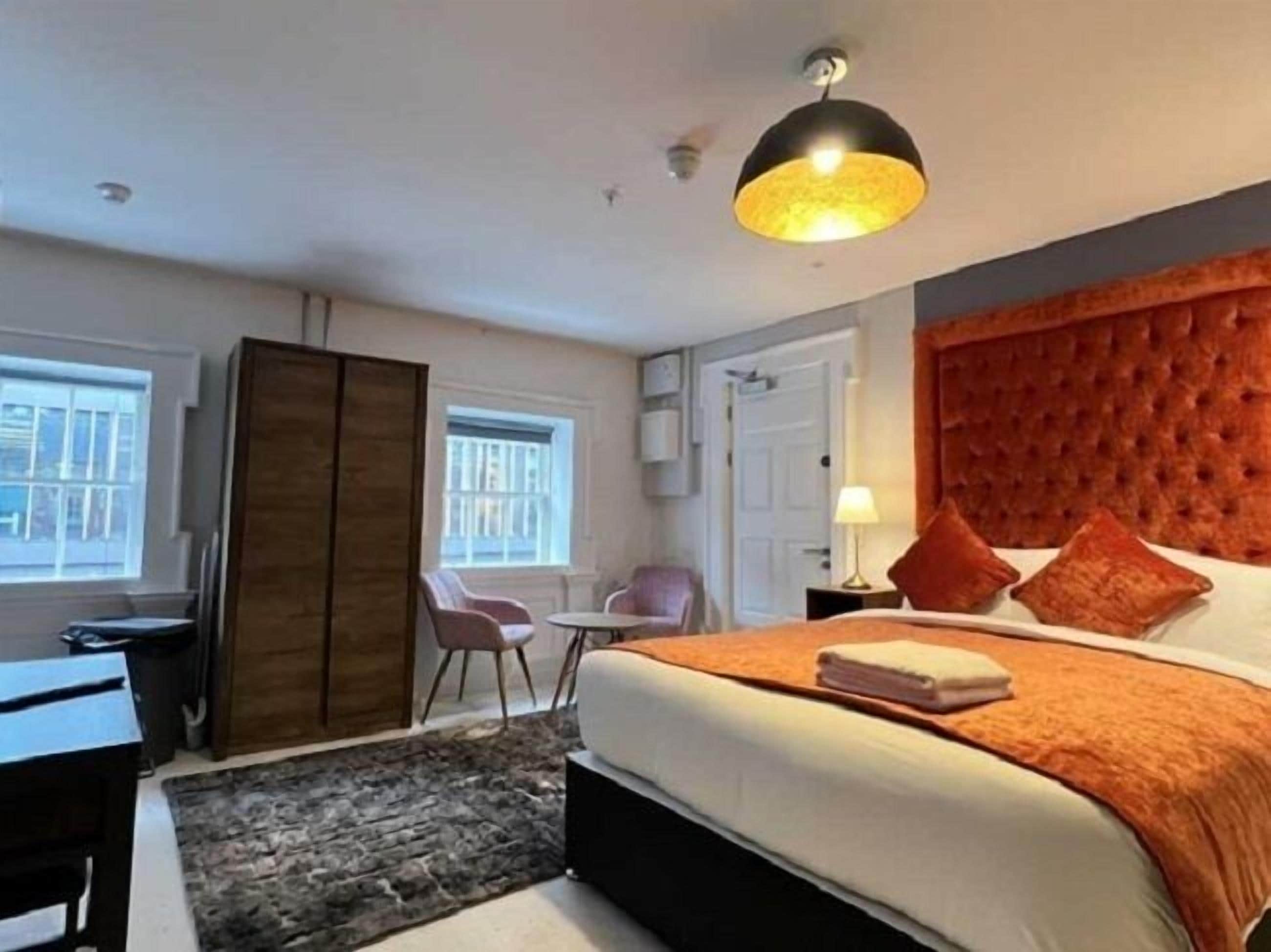 A modern bedroom with a large bed, a wooden wardrobe, a desk, and a chair.