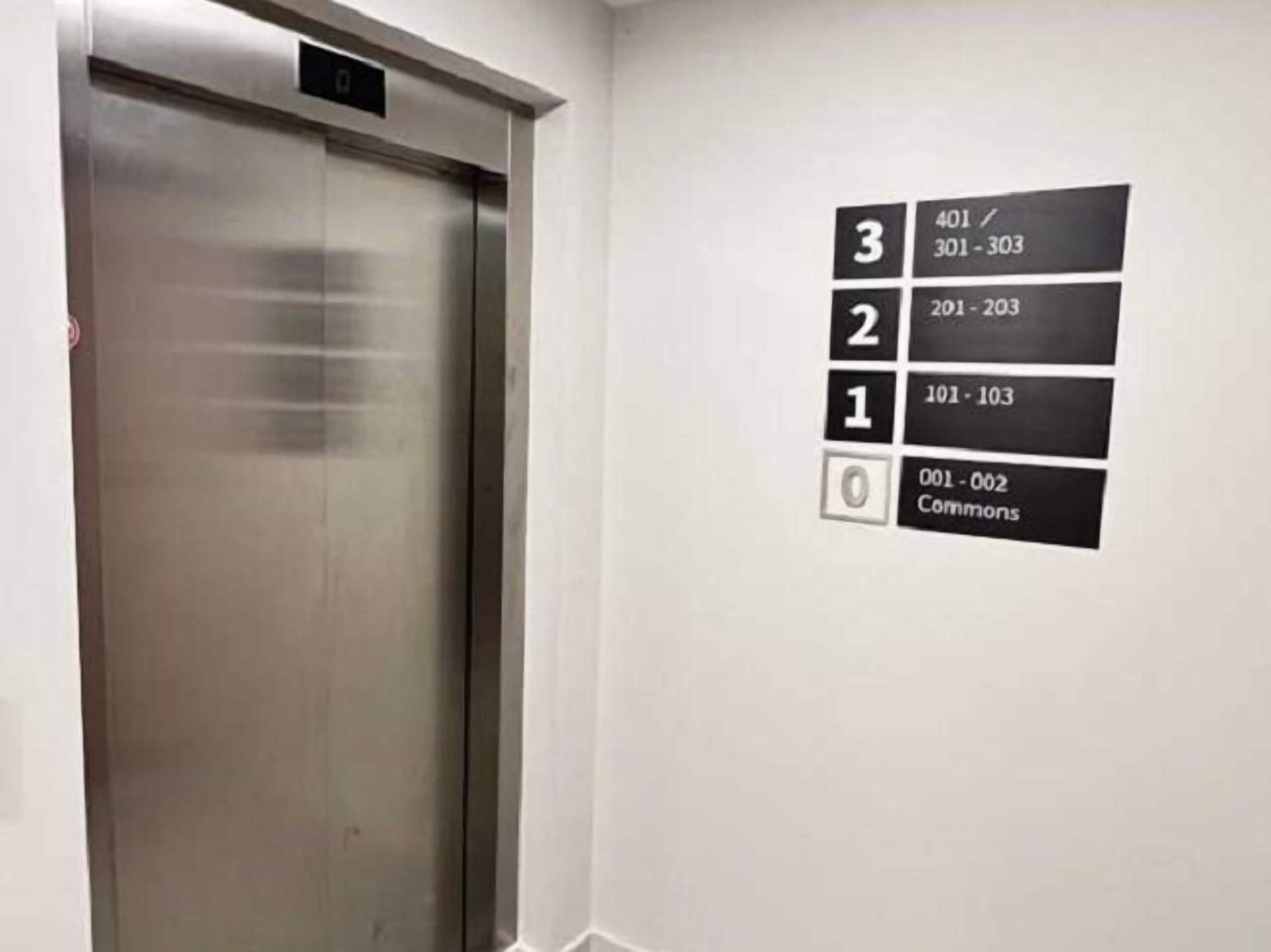 An elevator with a digital floor indicator displaying 3, 2, 1, and 0, and a sign for "Commons" on the wall.