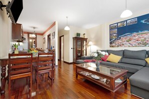 A living room with a sofa, a coffee table, and a dining area with chairs and a table.