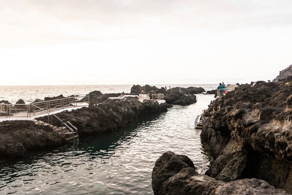 A rocky coastal area with a wooden walkway leading to a rocky outcrop.