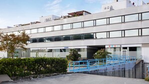 Un edificio moderno con fachada plana, ventanas amplias y una escalera azul que conduce a una entrada.