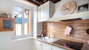 A kitchen with a wooden countertop, white cabinets, a built-in stove, and a window with a view of the outdoors.