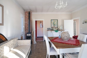 A cozy living room with a sofa, a dining table with chairs, a chandelier, and a kitchen area in the background. - Apartment 'Sweet Caselle' with Mountain View, Shared Garden and Wi-Fi (Testico)