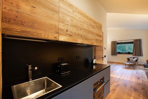 A modern kitchen with a black countertop, stainless steel sink, and wooden cabinets.