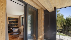 Een modern interieur met een houten plafond, een schuifdeur naar een buitenruimte, een bank, een kleine tafel en een boekenkast.