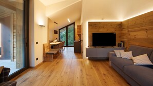 Een moderne woonkamer met een bank, televisie en houten wanden.