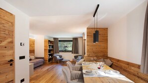 A modern interior with a dining area, wooden walls, and a view through a window.