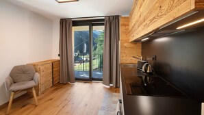 A modern kitchen with a wooden cabinet, a built-in stove, and a sliding glass door leading to a balcony.
