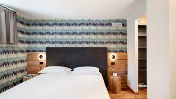 Un dormitorio con cama, cabecera de madera, dos lámparas de noche, mesita de noche y armario.