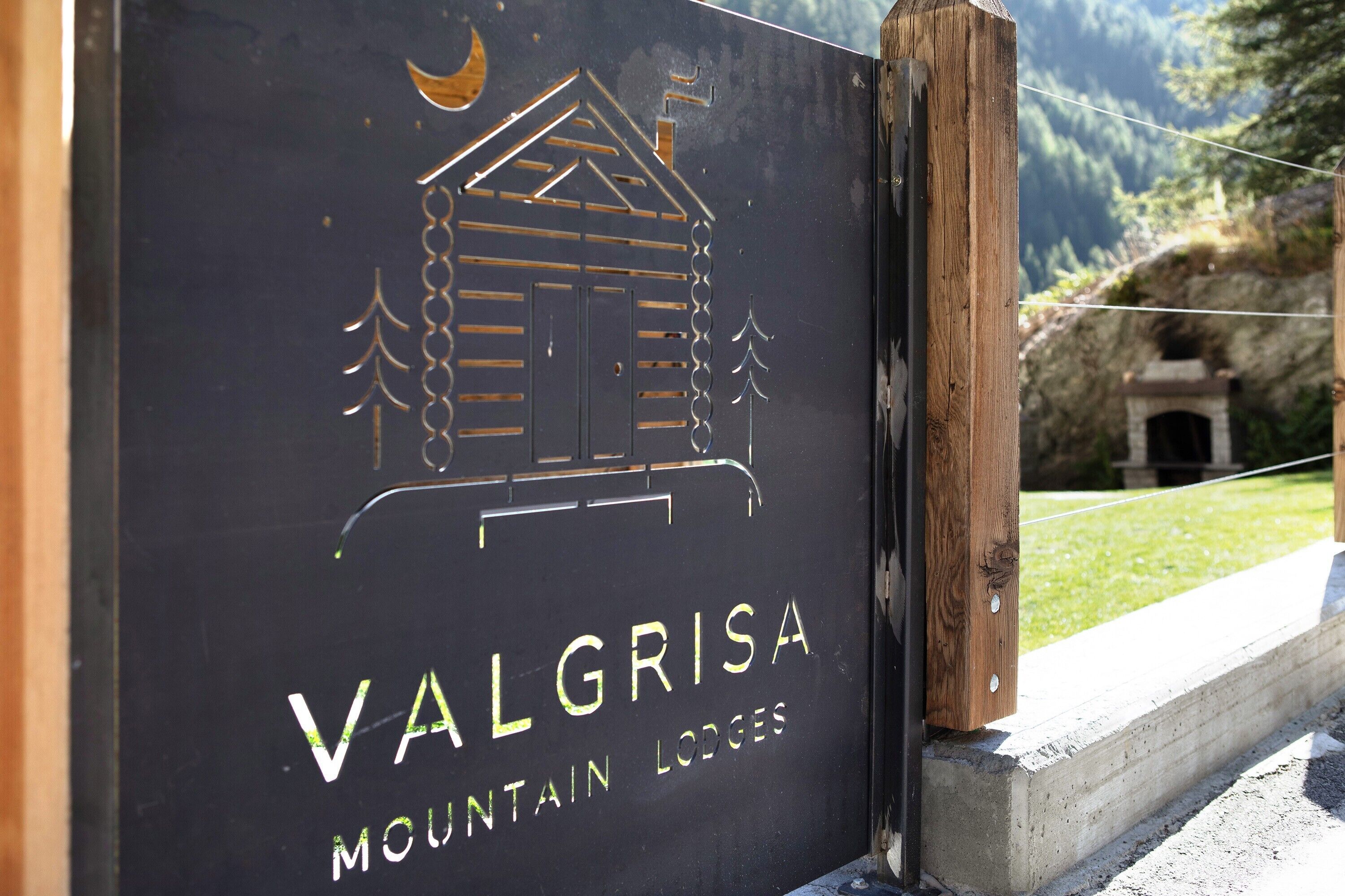 Une enseigne pour les refuges de montagne de Valgrisa, avec une illustration représentant un chalet de montagne.