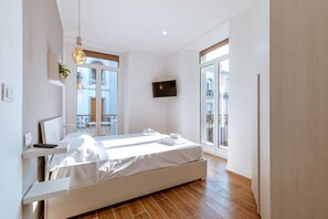 A modern bedroom with a bed, bedside tables, a TV, and large windows. - Central House Naples (Naples)