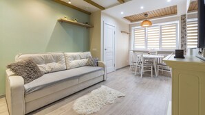 Una sala de estar moderna con un sofá, un tapete mullido y un comedor con una mesa y sillas.
