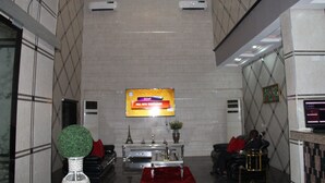 Eine Lobby mit Empfangsschalter, Fernseher und einer Sitzecke.