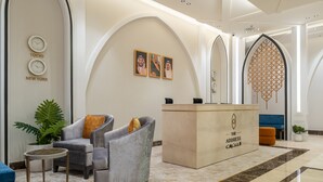 A modern lobby with a reception desk, seating area, and decorative wall elements. - Alenwan Serviced Apartments (Al Khobar)