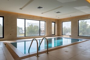 Piscina interna com ampla vista para o exterior através de grandes janelas.