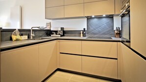 A modern kitchen with a built-in oven, a coffee machine, and a knife block.