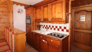 A wooden kitchen with a tiled backsplash, a built-in oven, and a sink. - Comfortable apartment with terrace and WIFI - 6 pers (Tignes)