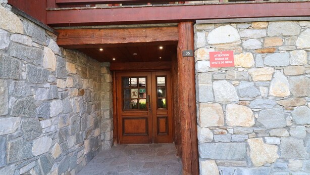 A stone building entrance with a wooden door and a balcony above. - Comfortable apartment with terrace and WIFI - 6 pers (Tignes)